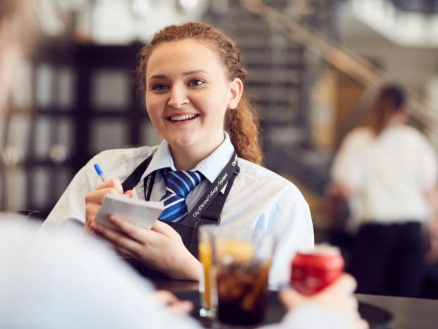A young, smiling woman from żapp takes an order